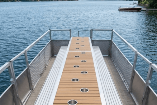 Pontoon boat deck with wood paneling and cup holders, lake view.