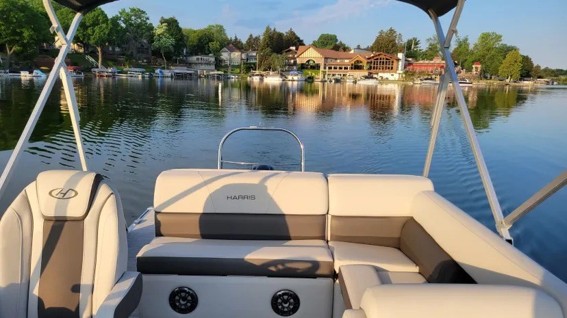 View from boat interior with lake houses and trees reflected on water.