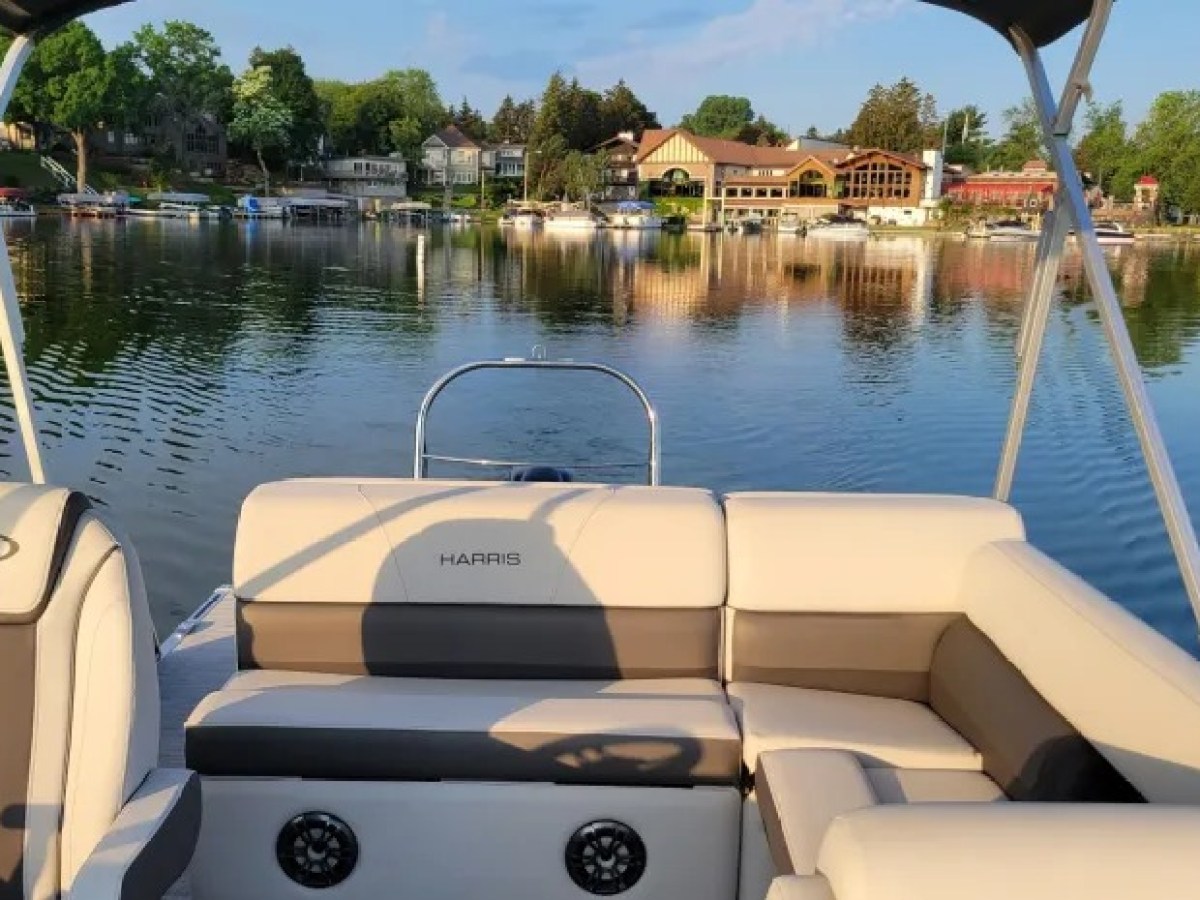 View from boat interior with lake houses and trees reflected on water.