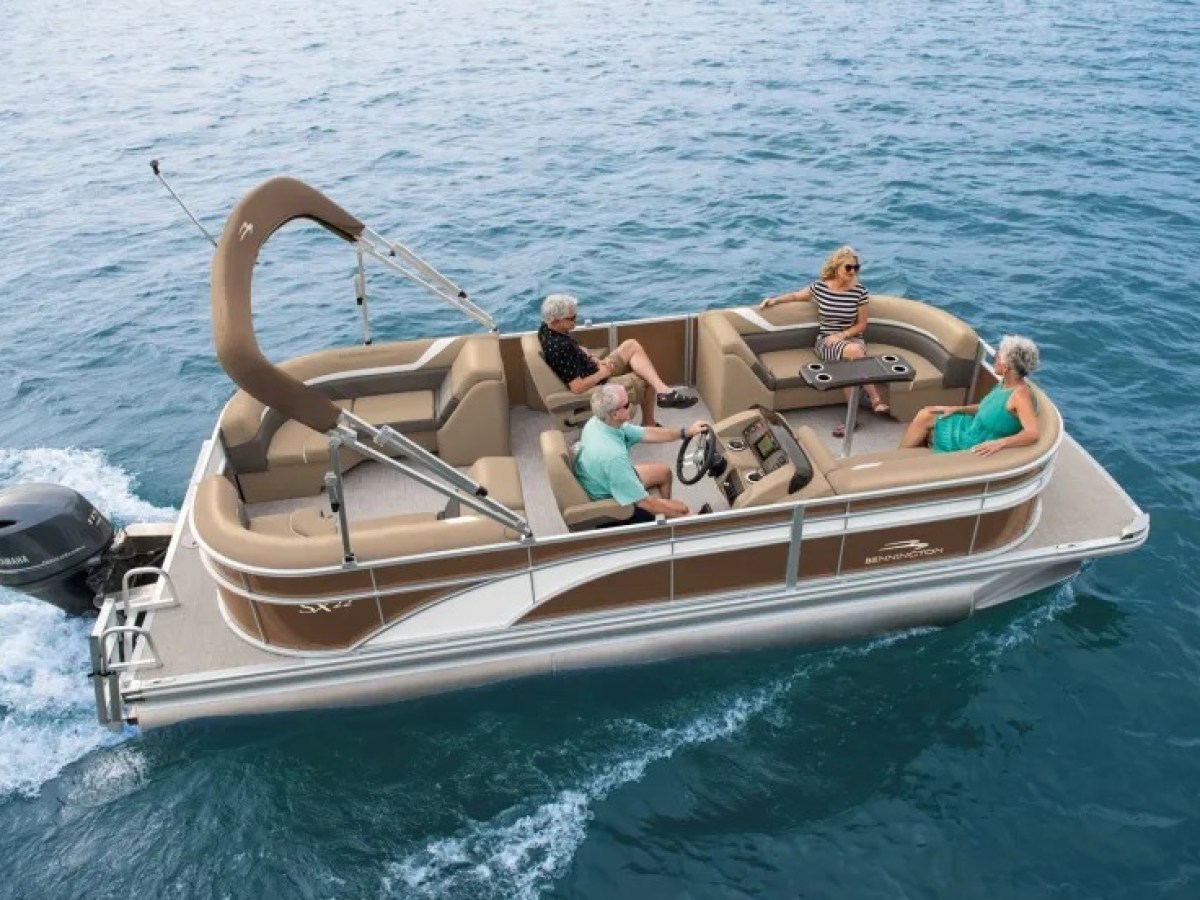 Four people relaxing on a pontoon boat in open water.