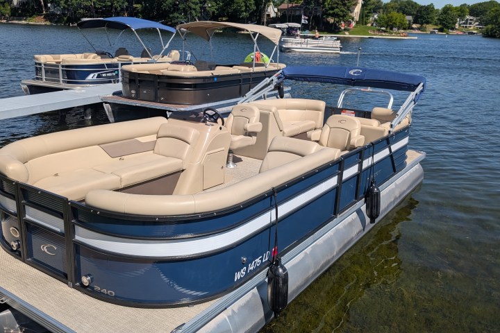 Blue and beige pontoon boat docked on a lake.